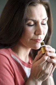 a brunette woman inhaling an essential oil