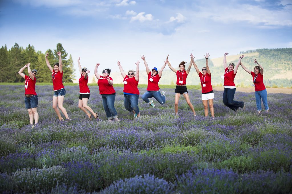 Seven women in red t-shirts jumping in a lavender field.